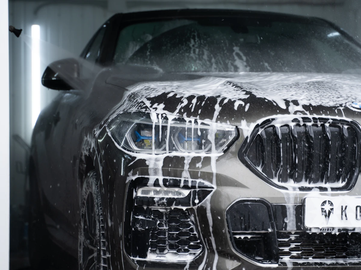 A dark car covered in white soap foam